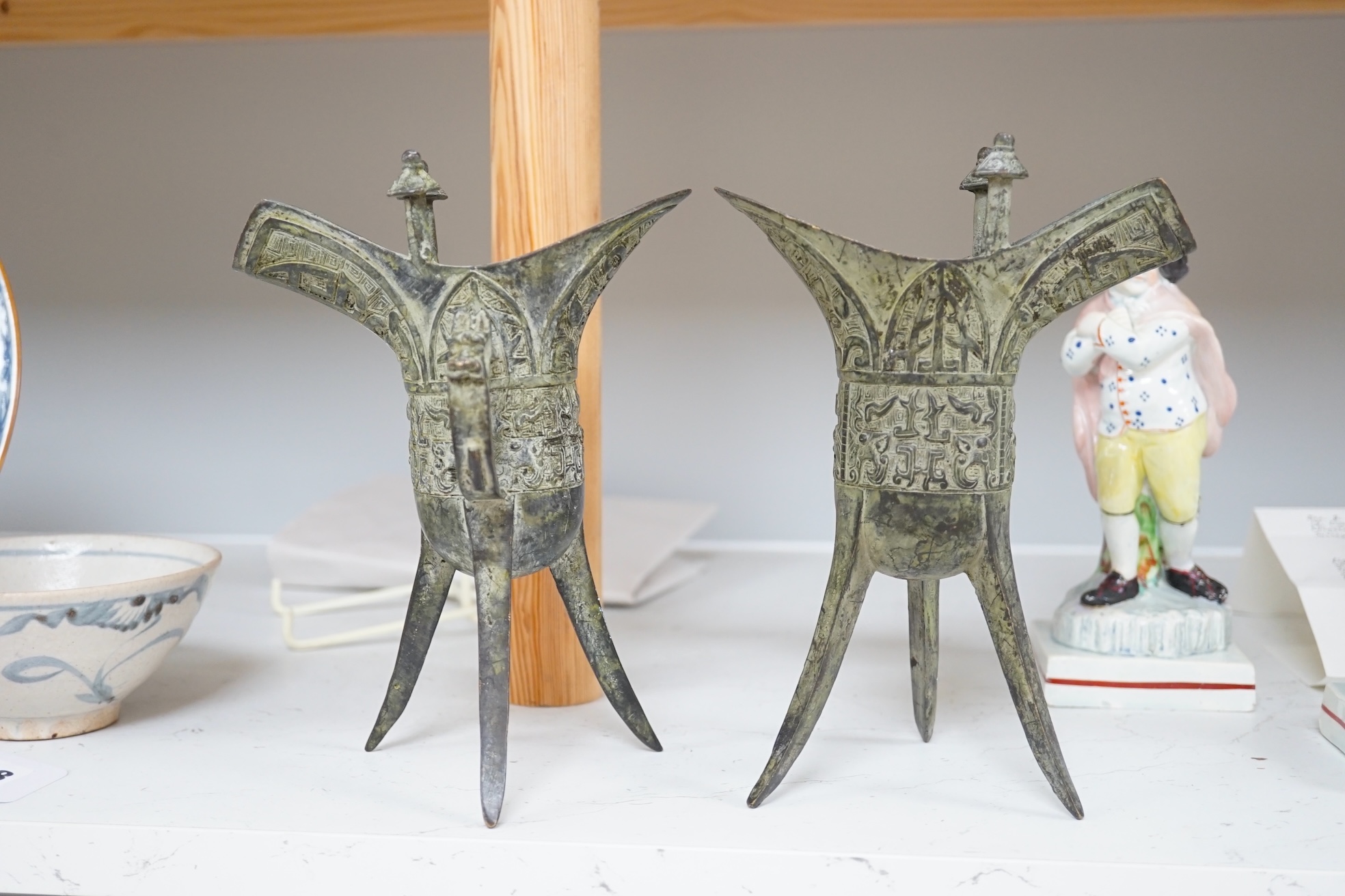 A pair of Chinese archaistic bronze vessels on tripod legs, jue, 20.5cm high. Condition - fair.